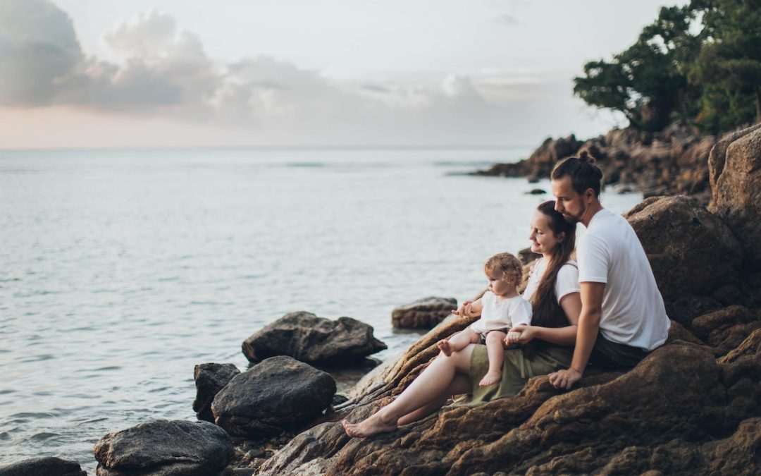 Family sitting on rocks by the water