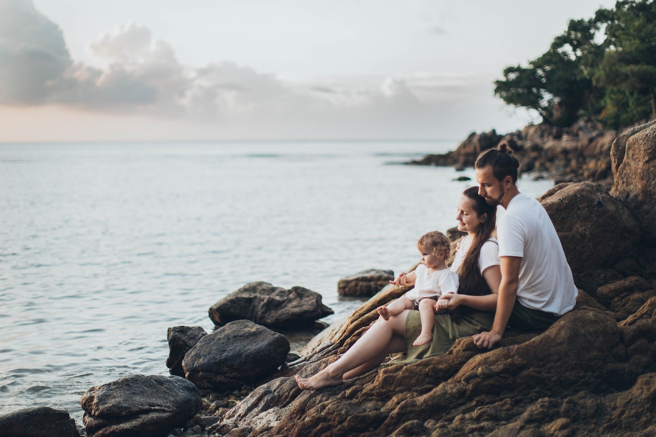 Family sitting on rocks by the water