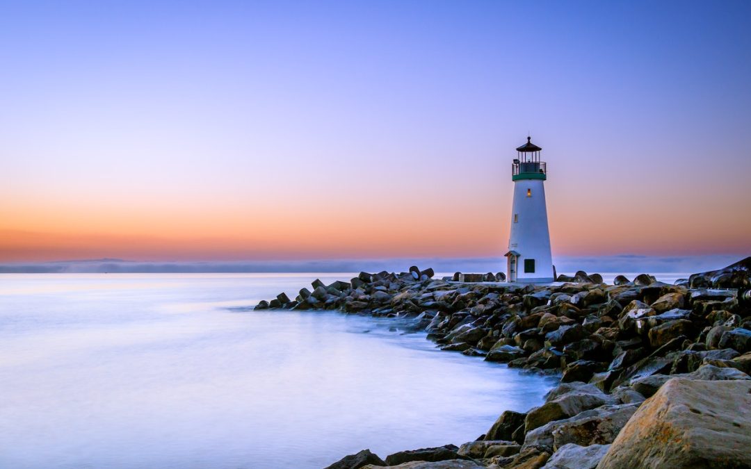 White lighthouse on a rocky coastline at dusk