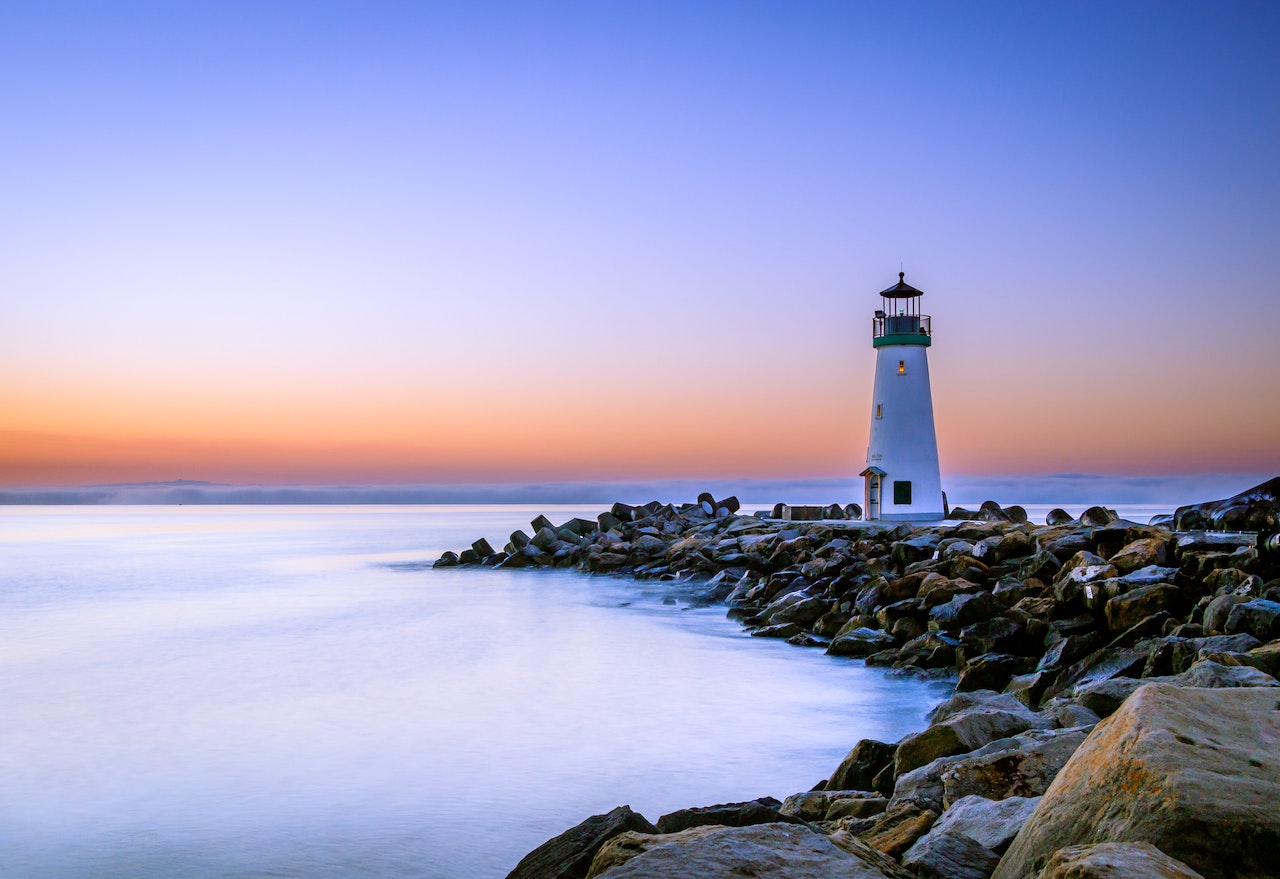 White lighthouse on a rocky coastline at dusk